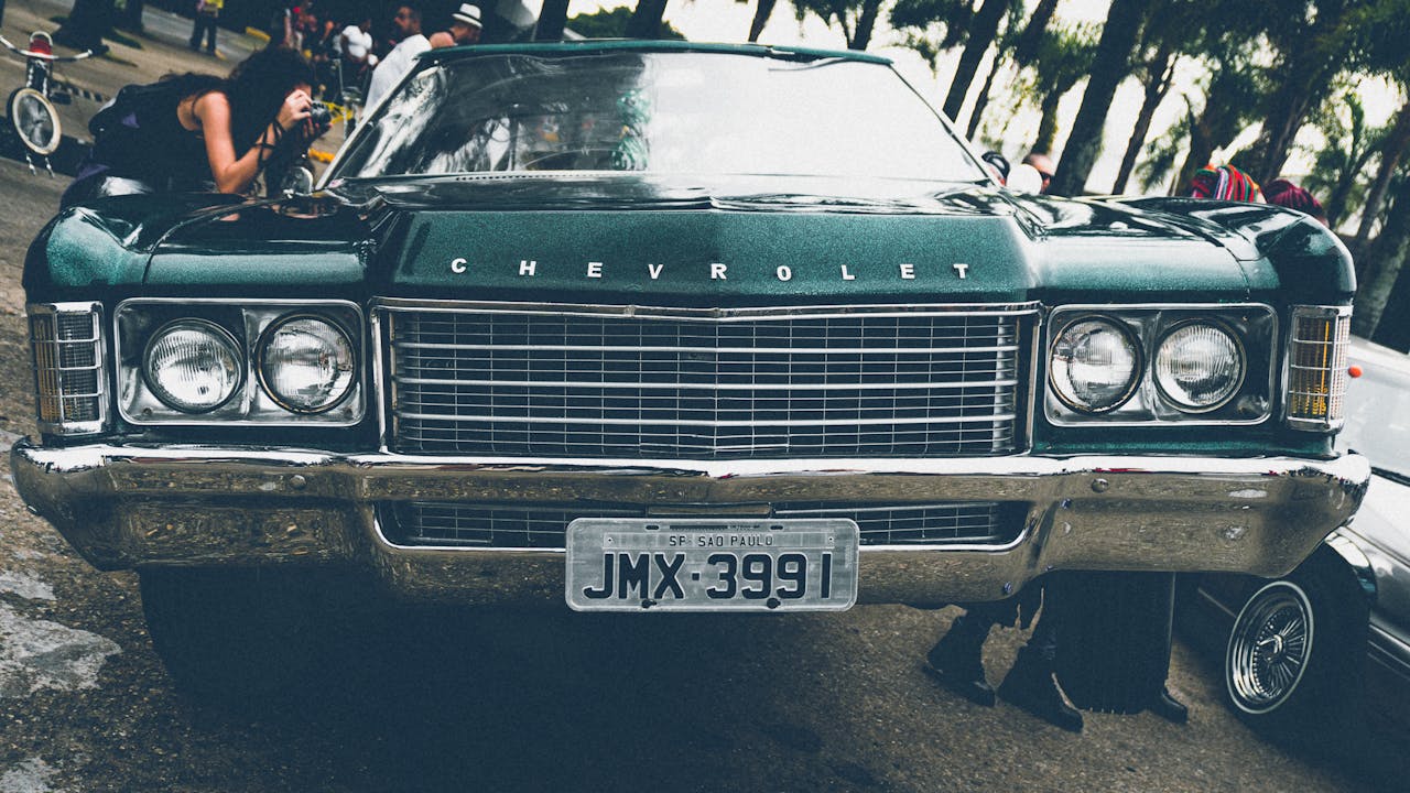 A vintage Chevrolet on display at an outdoor car show with onlookers admiring its design.